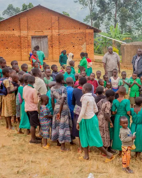Children gathered outside a brick school building for assembly