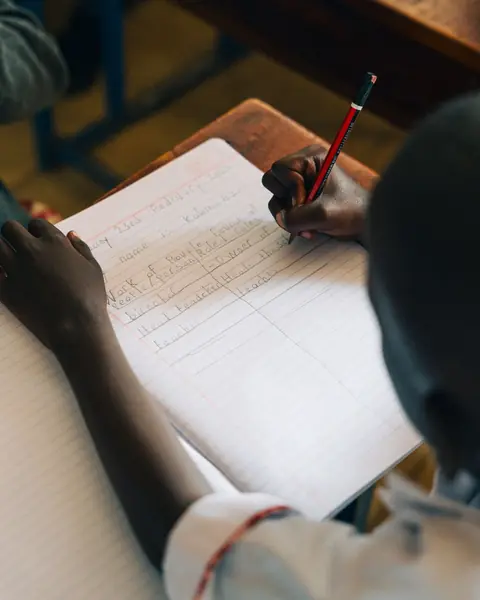 A pupil's hand writing in an exercise book